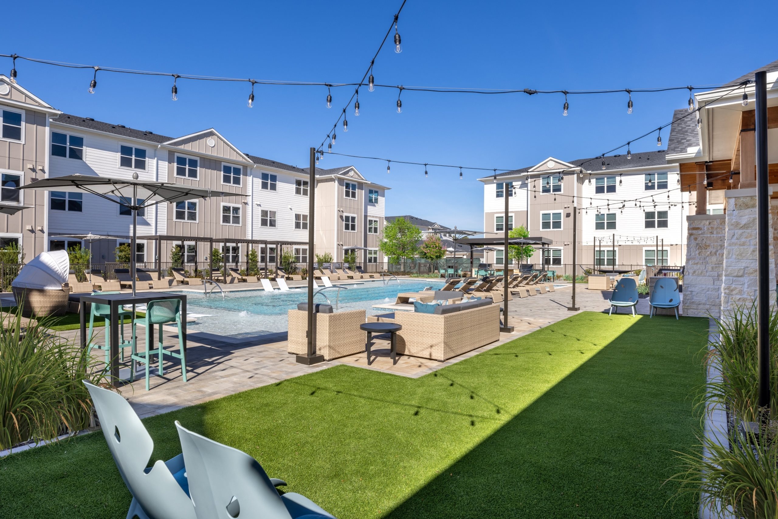 an outdoor amenities area with a swimming pool and grass